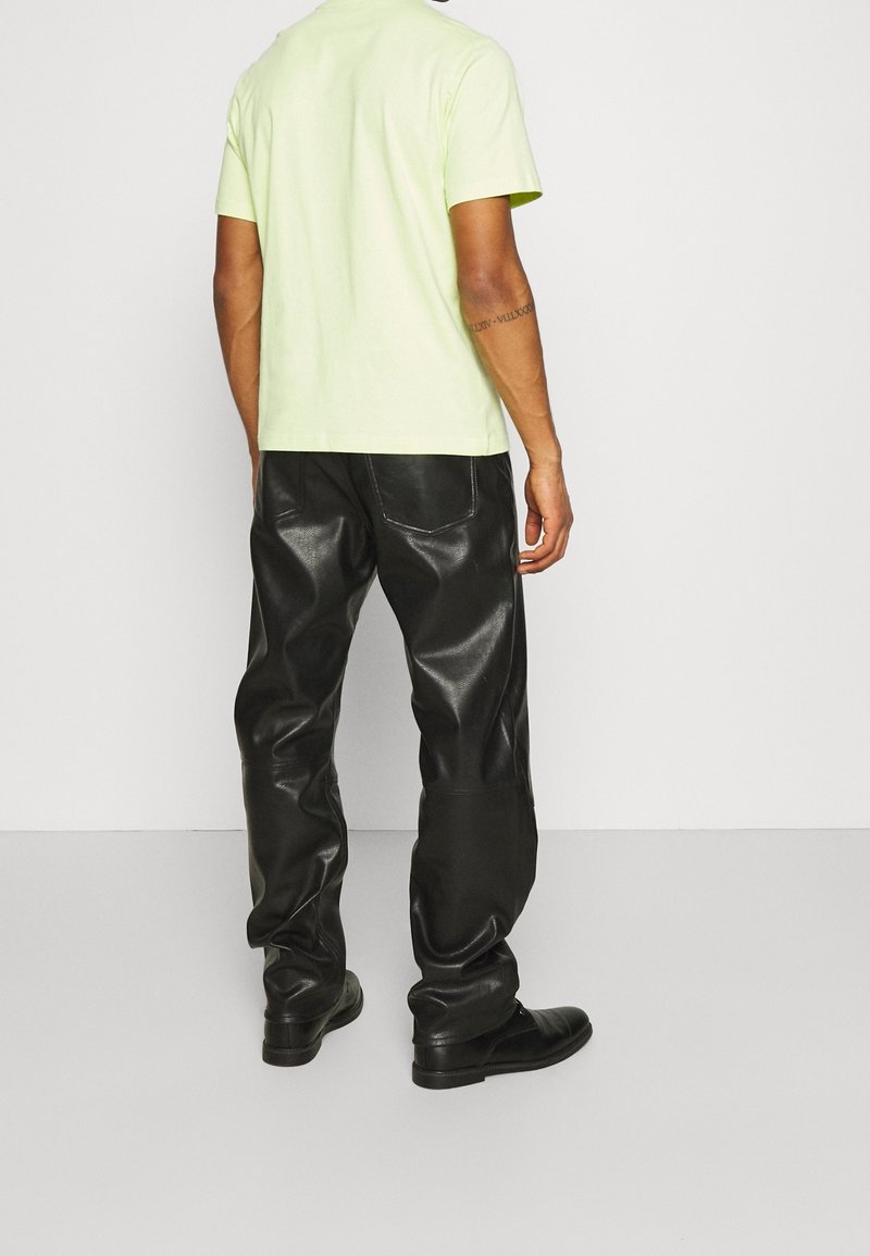Light green short-sleeve t-shirt paired with black leather trousers. Trousers have a glossy finish and visible stitching details.