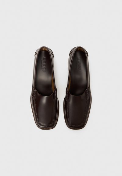 Scarpe in pelle marrone con punta quadrata, design slip-on e cuciture minime. Texture liscia, foderatura interna visibile, marchio impressa all'interno.
