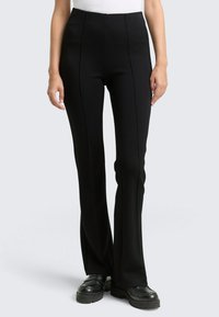 Schwarze maßgeschneiderte Hose mit hoher Taille, die sichtbare Vordernaht und einen geraden Beinausschnitt aufweist. Der Stoff wirkt glatt mit feiner Textur.