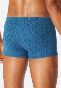 Blue patterned boxer briefs featuring a geometric design, soft fabric, and a low-rise waistband, shown from the back.