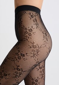 Pantys de red negras con patrones de encaje floral, con una cinturilla elástica ancha y una textura suave para mayor confort.