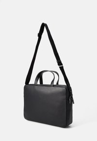 Sac en cuir noir avec deux poignées, bandoulière réglable et texture lisse. Forme rectangulaire avec une fermeture à glissière.