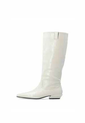 Botte haute en cuir blanc avec bout pointu et talon bas incliné, dotée d’un motif texturé subtil et d’une languette à l’arrière.