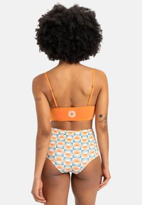 Top de bikini naranja con tirantes ajustables y logo, combinado con braguitas de talle alto con un patrón botánico en naranja y turquesa.