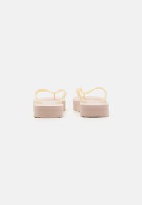 Pink platform flip-flops with a textured sole and yellow straps, featuring a smooth finish and curved strap design.