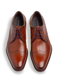 Zapatos de vestir de cuero marrón con una punta afilada y elegante, que presentan líneas horizontales sutiles y cordones azules en contraste. Textura suave y acabado pulido.