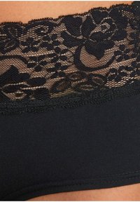 Black underwear featuring a floral lace band at the top, with a smooth, stretchy fabric below. Elegant scalloped edges on lace detail.