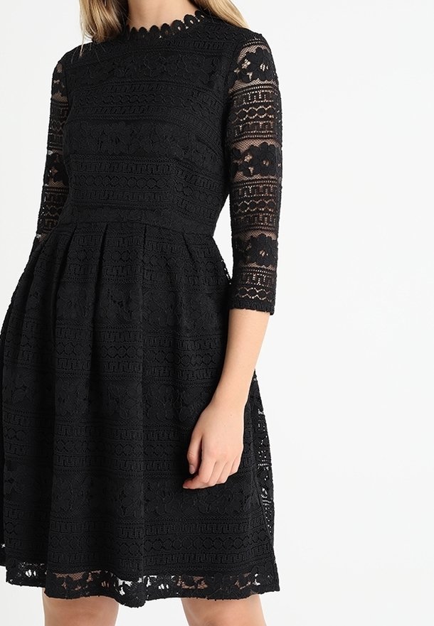 Svartrandad klänning i svart spets med trekvartsärmar, en figurnära överdel och en utställd kjol, med en scalloped ringning och intrikata mönster.