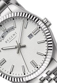Montre en argent avec un cadran blanc texturé, des index horaires en argent, une fenêtre de date et un bracelet en acier inoxydable poli. Présente une lunette cannelée.