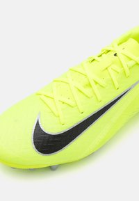 Neon keltainen jalkapallokenkä, jossa on teksturoitu materiaali, musta Nike-logoelementti ja tasaset kengännyörit. Ominaisuuksiin kuuluu kevytrakenne ja muotoillut piikit.