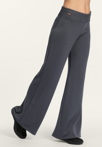 Dunkelgraue, weite Hose mit einem gerafften Bund, aus weichem, elastischem Stoff gefertigt. Sie verfügt über ein fließendes Design und subtile Seitennähte.