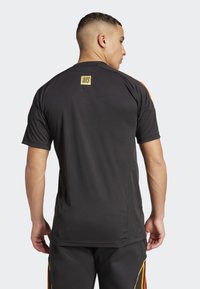 Black athletic t-shirt with short sleeves, featuring a yellow logo at the back and side mesh panels for breathability. Smooth texture.