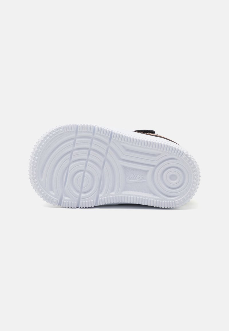 Semelle de sneaker Nike en caoutchouc blanc, présentant des motifs circulaires et linéaires avec un grip texturé et des détails de logo proéminents.
