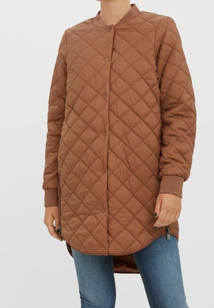 Veste longue matelassée marron avec un col rond, une fermeture à boutons et des poignets côtelés. Dispose de fermetures à glissière latérales et d'un ourlet légèrement plus long à l'arrière.