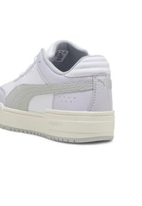 Fehér sneaker szürke részletekkel, texturált oldalsávval, párnázott bokréta résszel és vastag krém színű gumitalppal. Márkázás a sarokon és a nyelven.