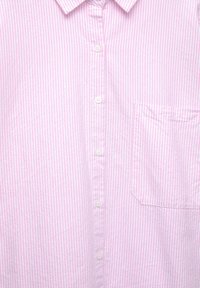 Camicia a righe rosa chiaro e bianca, realizzata in cotone. Presenta un colletto, cinque bottoni sul davanti e una tasca sul petto.