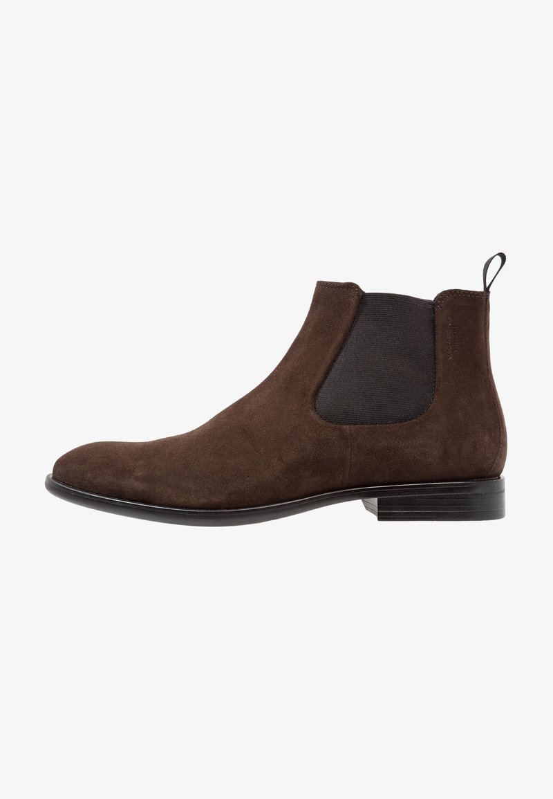 Bottine Chelsea en daim marron avec un panneau latéral élastique noir, un talon bas, un bout arrondi et un onglet à l'arrière.