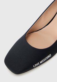 Black pointed-toe flat shoe with a smooth upper and "LOVE MOSCHINO" branding on the side against a white background.