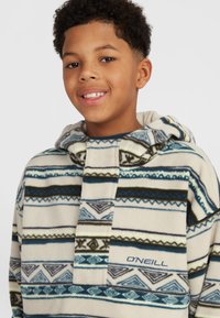 Fleece hoodie in beige met marineblauwe en turquoise geometrische patronen, voorzien van een voorvak en een capuchon met trekkoord. Logo aan de onderrand.