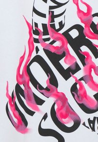 Černé tučné písmo s částečně viditelným textem a stylizovanými růžovými plameny na bílém pozadí, vytvářející dynamický grafický design.