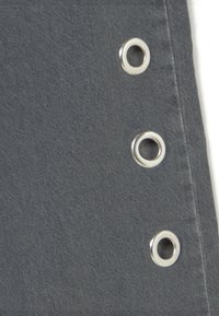 Tela gris con una fila vertical de tres ojales de metal plateado cerca del borde sobre un fondo blanco.