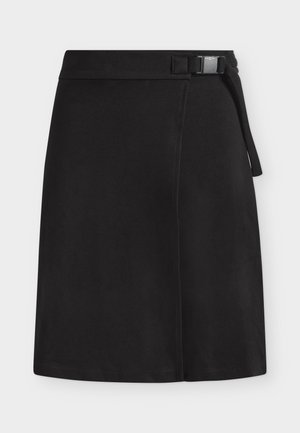 Jupe noire longueur genou à coupe droite avec un détail de ceinture à boucle latérale sur un fond clair uni.