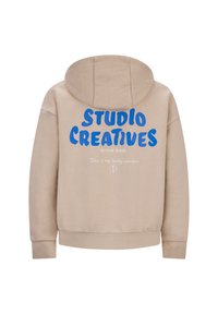 Beige hoodie met een trekkoord, voorzien van opvallende blauwe tekst "STUDIO CREATIVES" en "RETROUR JEANS" met daaronder een witte print. Zachte stoftextuur.