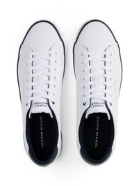 Sneakers bianchi a taglio basso con punta rotonda, lacci bianchi piatti e dettagli blu navy. Presentano una tomaia in sintetico liscia e una suola in gomma.