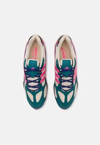 Teal and beige athletic shoes with pink accents, featuring a mesh upper, layered design, and multi-colored laces on a textured sole.