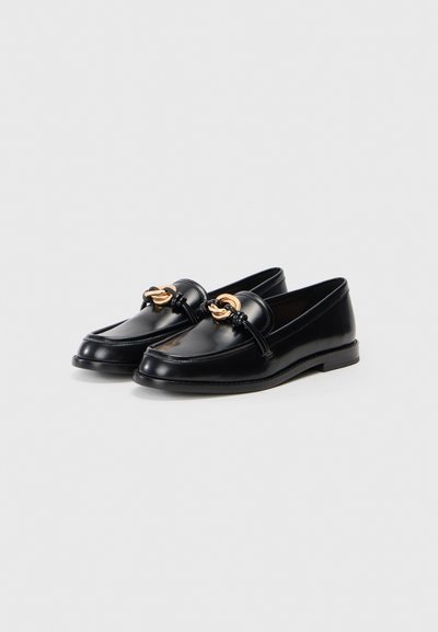 Black leather loafers with a round toe, featuring gold hardware accents and a visible stitching detail on the sole. Classic design.