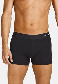Schwarze Boxershorts mit einer figurschmeichelnden Passform, aus weichem Baumwollstoff gefertigt. Merkmale einen flachen elastischen Bund mit Logo-Text.