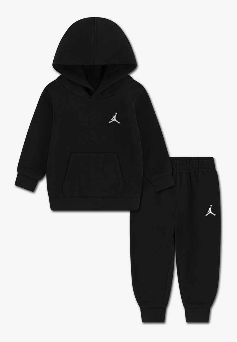 Zwart hoodie- en joggingpak gemaakt van zachte stof. Voorzien van een voorzak en witte logo-accenten op beide stukken. Casual, comfortabel ontwerp.