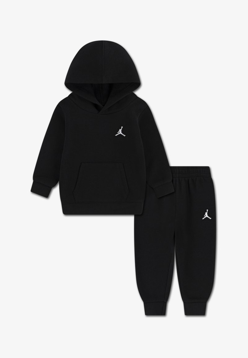 Zwart hoodie- en joggingpak gemaakt van zachte stof. Voorzien van een voorzak en witte logo-accenten op beide stukken. Casual, comfortabel ontwerp.