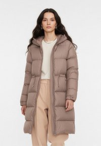 Kurtka puchowa w stonowanym beżowym kolorze, wyposażona w kaptur, zamek z przodu oraz boczne kieszenie z elastycznymi mankietami. Teksturowane body z przeszywanymi sekcjami.