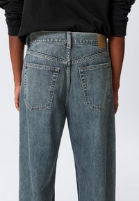 Ανοιχτό γαλάζιο τζιν με ίσιο κόψιμο, που διαθέτει δύο πίσω τσέπες, δερμάτινο ταμπελάκι στη μέση και διακριτικό ξεθώριασμα.