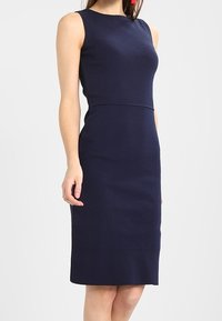 Laivasilmäsin, hihaton mekko, jossa on tiukka yläosa ja suora hame. Valmistettu sileästä kankaasta, jossa on hieno rakenne. Polvipituisuus.