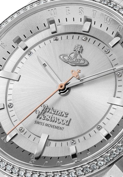 Zilveren roestvrijstalen horloge met een gestructureerde wijzerplaat, rosegouden wijzers en kristallen versieringen op de lunette. Bevat het merkje.