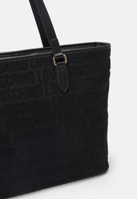 Černá taška přes rameno s raženým vzorem textu "LOVE MOSCHINO" a černými koženými držadly připojenými zlatým kováním.