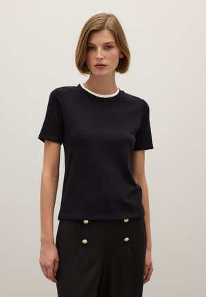 Camiseta negra de manga corta con cuello redondo que presenta un ribete blanco en contraste. Tejido suave, diseño ajustado y textura lisa.