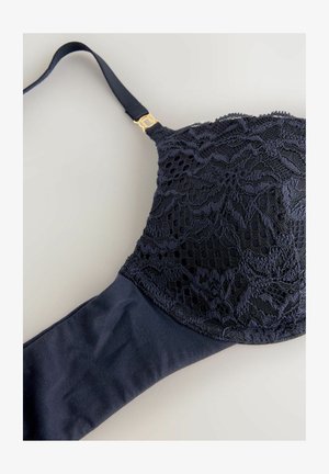 Bra blu navy con sovrapposizione in pizzo sulla coppa, tessuto liscio sulla fascia, spalline regolabili e dettaglio in metallo color oro.