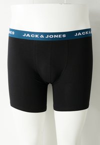 Schwarze Boxer-Briefs für Männer mit blauer Taille, die das weiße "JACK & JONES"-Logo auf einem weißen Mannequin-Oberkörper zeigen.