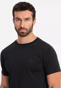 Sort kortærmet t-shirt lavet af blødt stof. Har en rund halsudskæring og en diskret logoaccent på brystet.