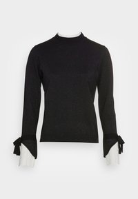 Pull noir à col montant et manches longues. Il présente un tissu texturé et scintillant ainsi que des poignets côtelés blancs contrastants ornés de nœuds.