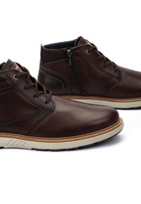 Brown leather ankle boots with a smooth finish, tonal stitching, and a side zipper. Light-colored rubber sole with a textured grip.