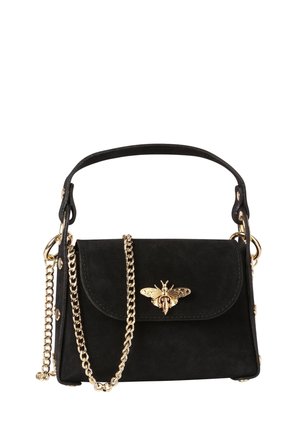 Sac à main en daim noir avec emblème d'abeille dorée sur le rabat avant, bandoulière chaîne dorée et poignée courte noire, présenté sur fond blanc.