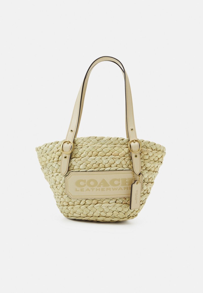 Tkanina słomkowa torba na ramię w jasnym żółtym kolorze z skórzanymi akcentami. Posiada podwójne uchwyty i wyraźnie widoczny emblemat na przedniej stronie.