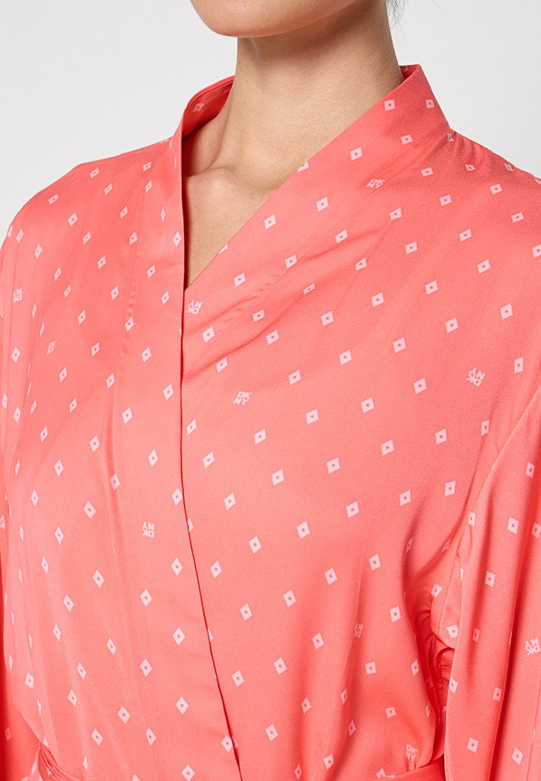 Korallfarbener Kimono mit Diamantmustern, hergestellt aus glattem Stoff. Verfügt über einen weiten Halsausschnitt und kurze Ärmel mit einer leichten, fließenden Textur.