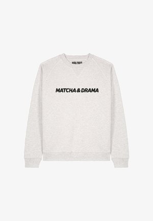 Sweatshirt gris avec un col rond et des manches raglan. Présente un texte noir audacieux "MATCHA & DRAMA" sur le devant. Texture douce.