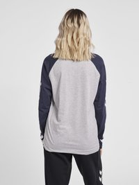 Grå långärmad topp med marinblå raglanärmar, med logodetalj på vänster ärm och en avslappnad passform. Mjuk bomullsblandning.