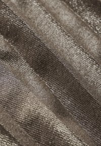 Metallisk stickad tyg med ojämn textur, som har växelvisa ränder av mörkgrått och silver, vilket skapar en skimrande effekt.